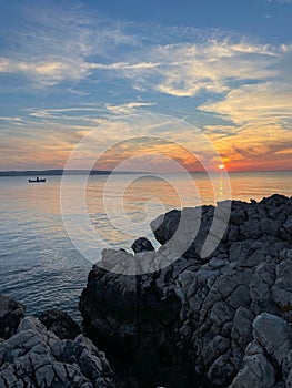 Vertical shot of the sea at sunset with a boat silhouette in the background