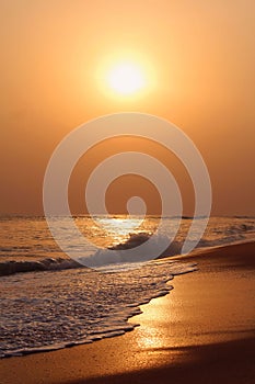 Vertical shot of seawaves covering the coastline in the sunset