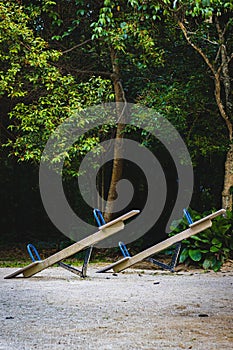 Vertical shot of seesaws on the coast with a forest on the background