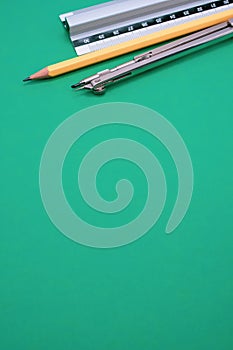 Vertical shot of a set of technical drawing tools on a green background with a copy space