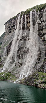 Vertical shot of the Seven Sisters Waterfall under cloudy sky in More og Romsdal county, Norway.