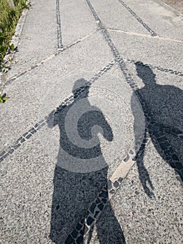 Vertical shot of shadows of two people on the ground