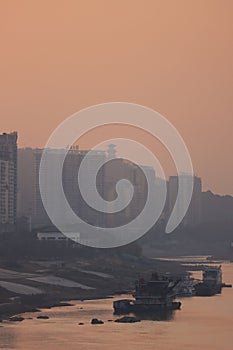 Vertical shot of ships near a coast with a background of buildings