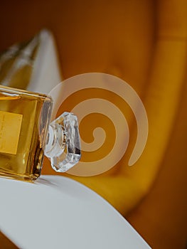 Vertical shot of a sideway an aesthetic clear perfume bottle with gold substance on furniture