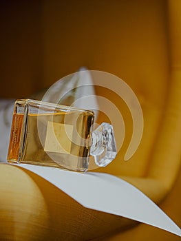 Vertical shot of a sideway an aesthetic clear perfume bottle with gold substance on furniture