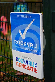 Vertical shot of sign in Dutch language saying that the area is smoking-free by a playground