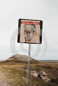 Vertical shot of a sign showing a warning to be beware of bison