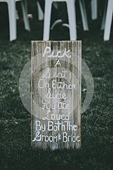 Vertical shot of signage, pick a seat either side on a wedding day with a blurred background.