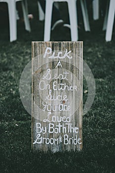 Vertical shot of signage, pick a seat either side on a wedding day with a blurred background. photo