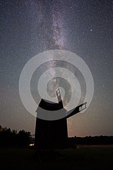 Vertical shot of the silhouette of a windmill under the Milky Way constellation at night