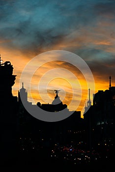 Vertical shot of the silhouettes of the buildings with lights at sunset in Gran Via, Madrid, Spain photo