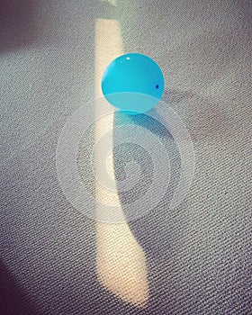 Vertical shot of single blue balloon on the carpet with reflection of sunlight