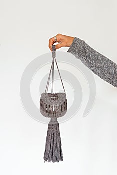 Vertical shot of a single macrame candle hanger held by a female isolated on a white background