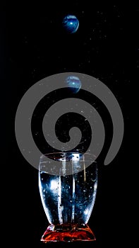 Vertical shot of the small balls walling into a glass with water