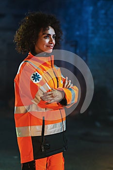 Vertical Shot: Smiling Female Paramedic Looking at Camera and Posing with Crossed Hands. A Strong