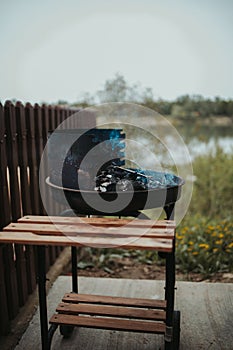 Vertical shot of smoke rising from embers on a fire pit in backyard next to a wooden fence