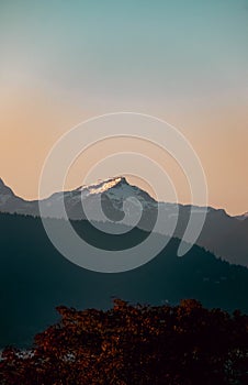 Vertical shot of a snow-capped mountain peak under the golden sunset sky