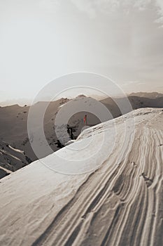 Vertical shot of a snow-covered field with a flagpole and viewpoint on the background