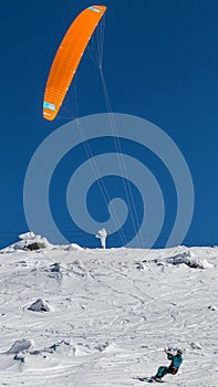 Vertical shot of a snowborder with snow kite against a blue sky