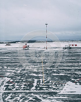 Vertical shot of a snowy airplane airstrip with  a couple of airplanes on a cloudy day