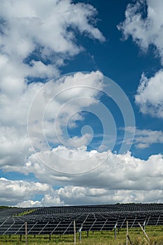 Vertical shot of solar panels in the field in the countryside under the cloudy sky