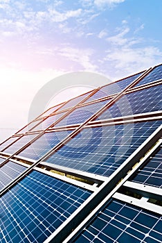 Vertical shot of solar panels with sunset and blue sky backgroun