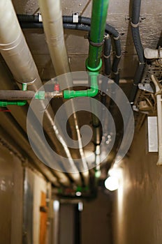 Vertical shot of some metal pipes on a ceiling of a basement corridor