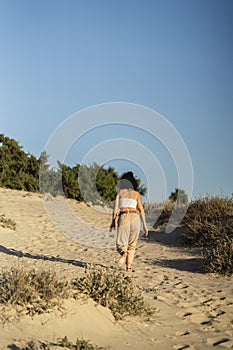 Vertical shot of a Spanish female posing walki on the sand