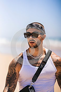 Vertical shot of the Spanish, young man with tattoos at the beach