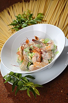 Vertical shot of spinach pasta with fresh shrimp and guajillo chili on a white salad plate