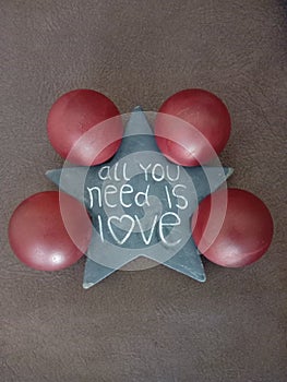 Vertical shot of a star with a quote  all you need is love and four red balls on the floor