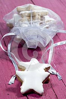 Vertical shot of star-shaped cinnamon cookies with white icing on a pink wooden surface