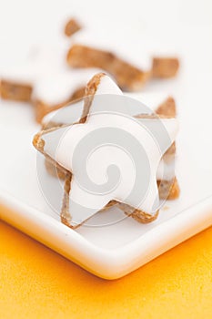 Vertical shot of star-shaped cinnamon cookies with white icing on a white plate