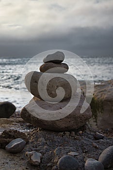 Vertical shot of a stone balance on the beach and sea in the background