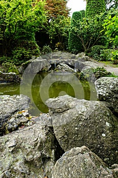 Vertical shot of stones around the pond in the fall in a Japanese garden