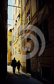 Vertical shot of strangers walking in the narrow street. Finale Ligure, Italy