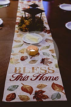 Vertical shot of a table runner with bless the home written on it