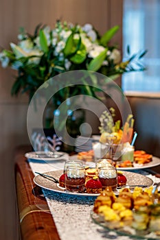 Vertical shot of a table setting with a flower bouquet decoration and delicious shok manje dessert