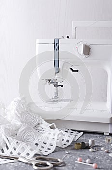 Vertical shot of tailor`s workplace.Sewing machine,white fabric,scissors and different accessories for sewing clothes