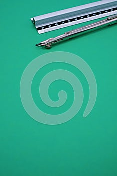 Vertical shot of technical drawing tools on a green background with a copy space