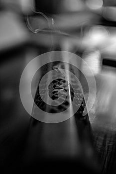 Vertical shot of a thin stream of smoke from an incense burner in grayscale