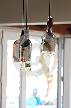 Vertical shot of three bottles hung from lamp wires