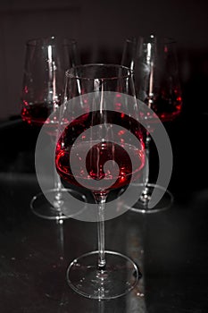 Vertical shot of three glasses of red wine in dim lig