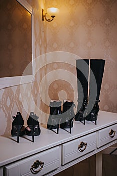 Vertical shot of three pairs of black high heel shoes on the table in the room