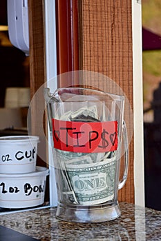 Vertical shot of tips jar on an outside window counter of a restaurant