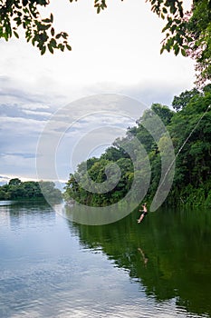 Vertical shot of a tourist diving from a rope swing at the Peten Itza Lake in Flores, Guatemala