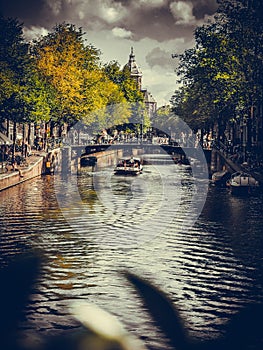 Vertical shot of a touristic canal in Amsterdam and the Basilica of Saint Nicholas in the background