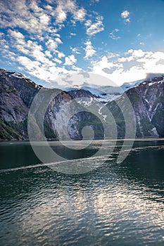 Vertical shot of the Tracey Arm fjord in Alaska near Juneau with a cloudy blue sky in the background