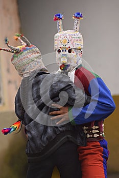 Vertical shot of Traditional Tricksters of the Saraguro culture wearing masks and dancing photo