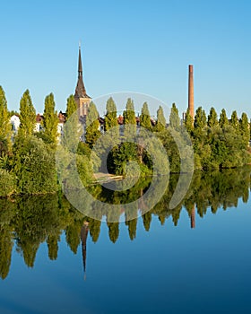 Vertical shot of trees ad buildings reflecting in the water.